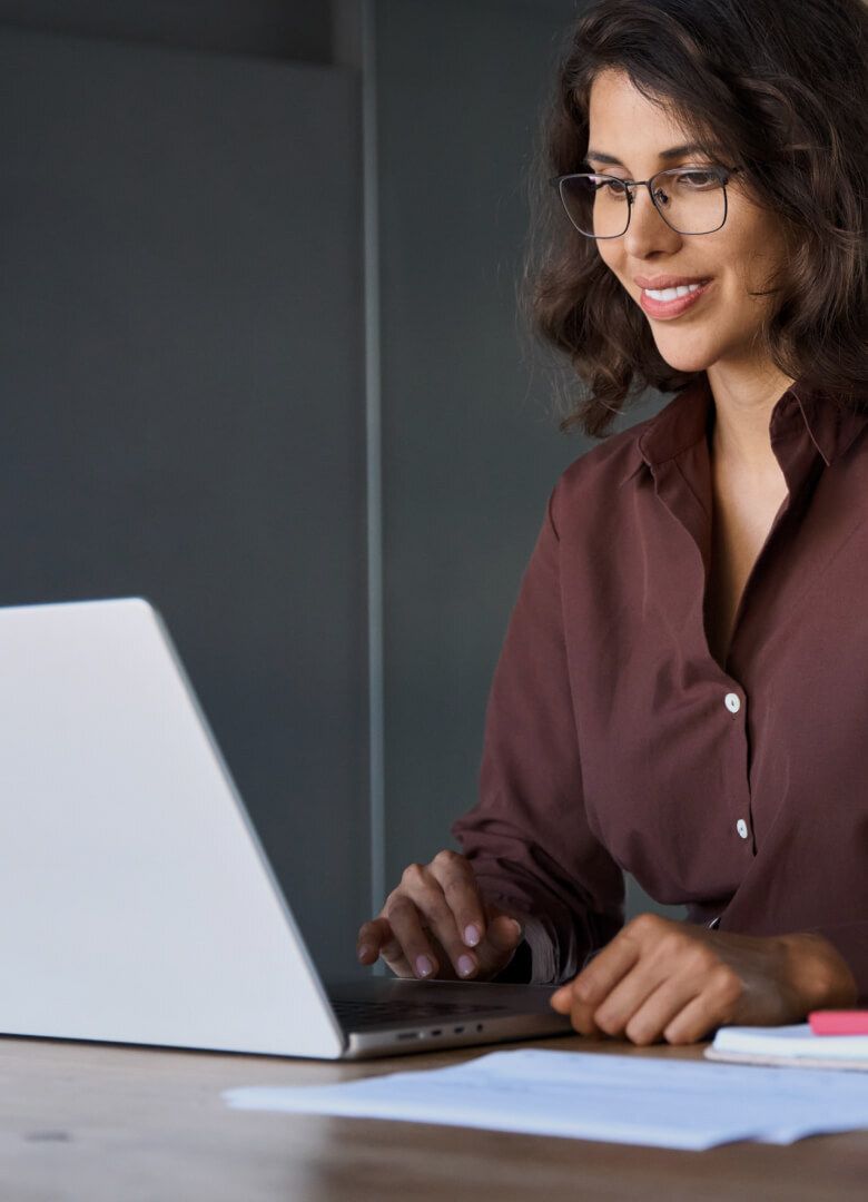 Smiling professional woman working on laptop in office – Neutrinos