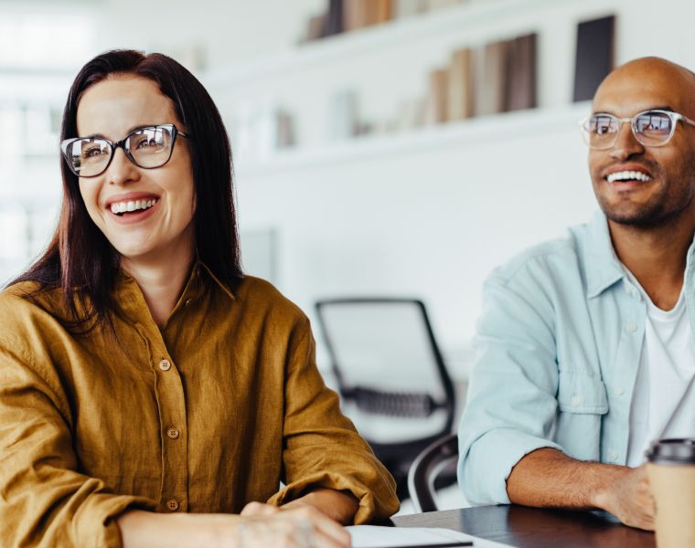 Two smiling professionals in a meeting room, appearing engaged in a discussion- Neutrinos