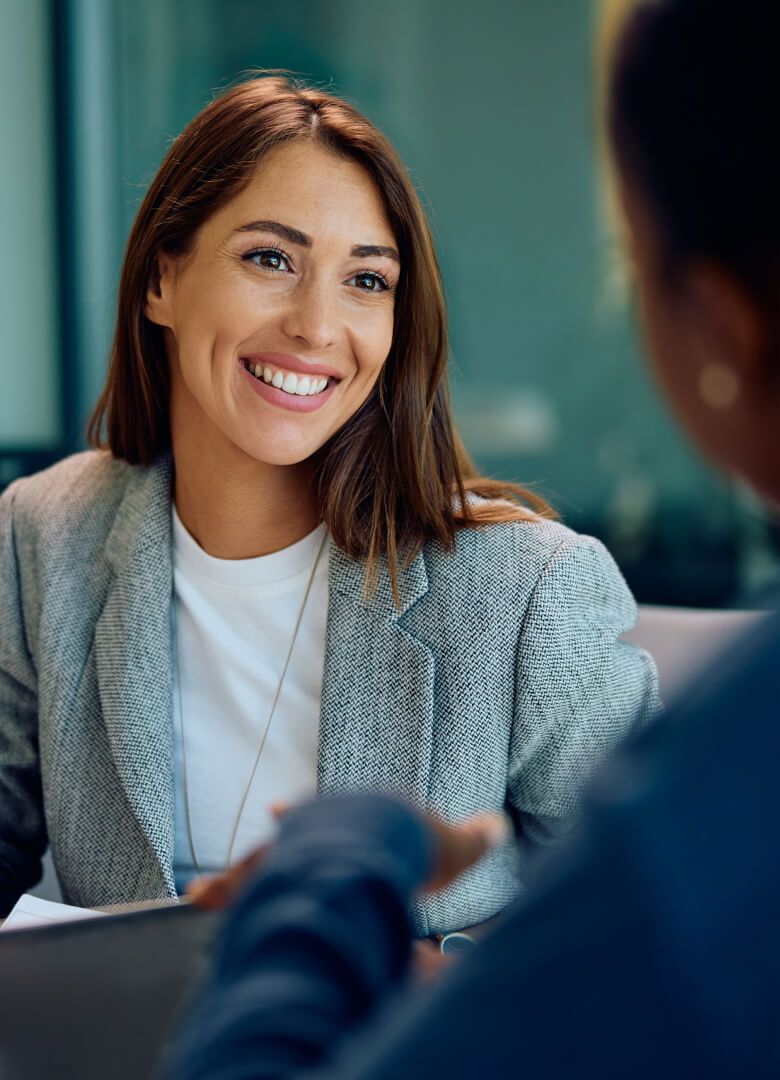 Smiling professional woman in a grey blazer engaging with customer-Neutrinos