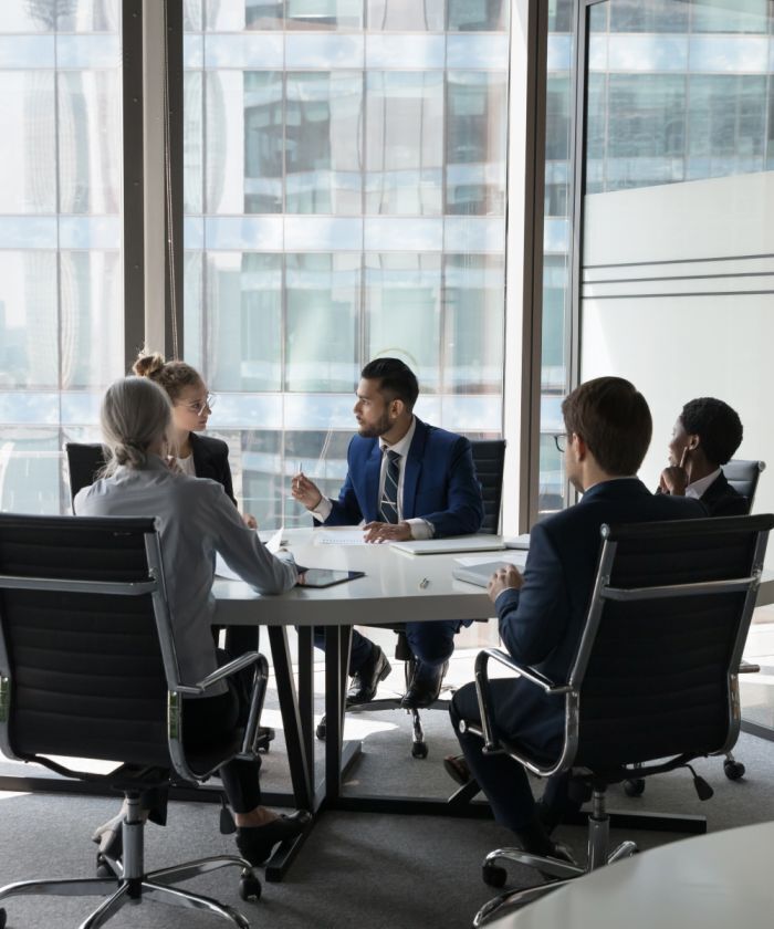 Diverse team in formal meeting in a glass-walled office – Neutrinos