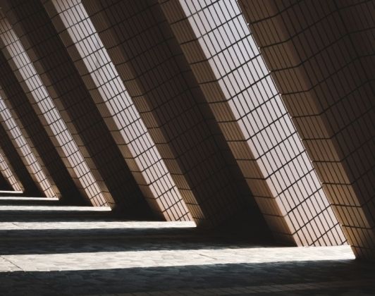 Diagonal architectural columns casting patterned shadows-Neutrinos