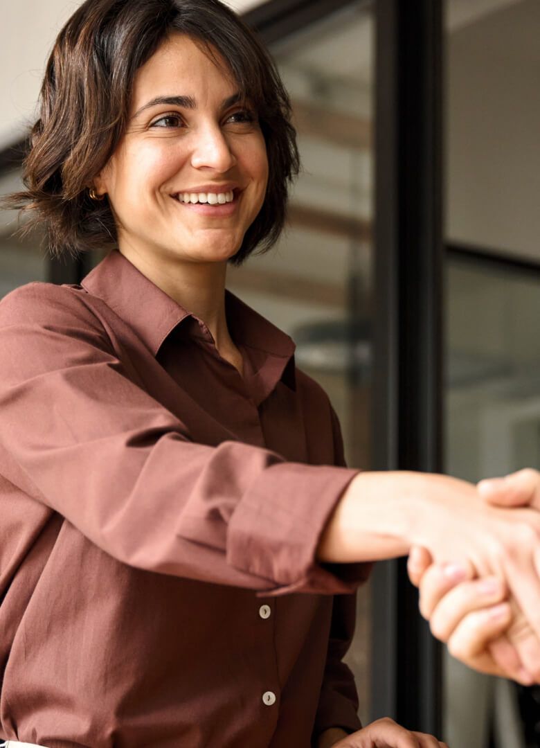 Businesswoman offering a handshake in a collaborative workspace environment - Neutrinos