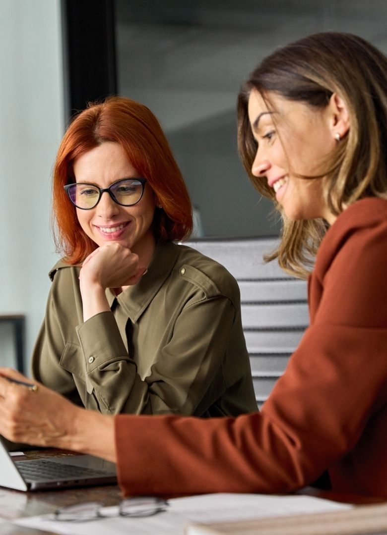 Two businesswomen collaborating over a laptop in a modern office – Neutrinos