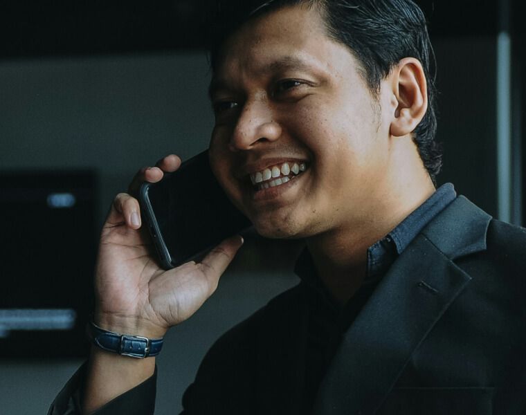 Smiling man in a blazer talking on a mobile phone indoors-Neutrinos
